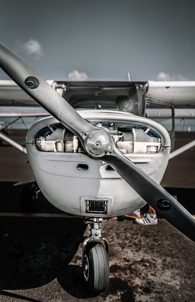 Modern white basic trainer aircraft with propeller parked on airfield on sunny day